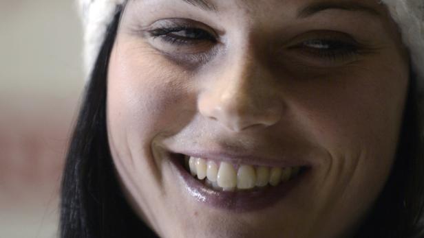 Nahaufnahme einer lächelnden Frau mit dunklen Haaren und einer weißen Mütze.