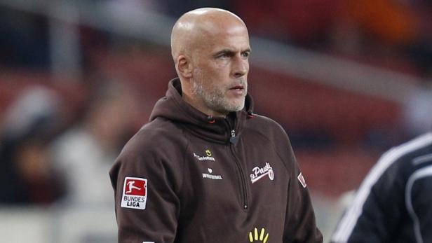 Ein Mann mit Glatze und Bart trägt einen braunen St. Pauli Trainingsanzug.