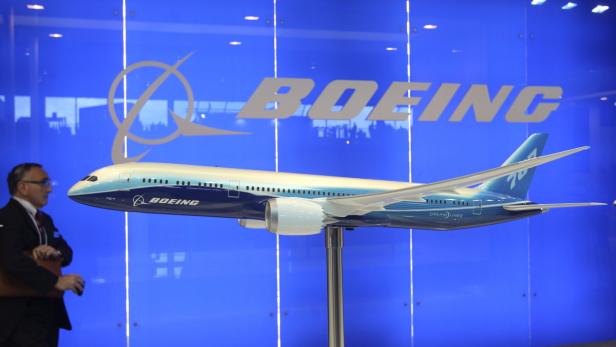 Ein Modell eines Boeing 787 Dreamliner vor einem blauen Hintergrund mit dem Boeing-Logo.
