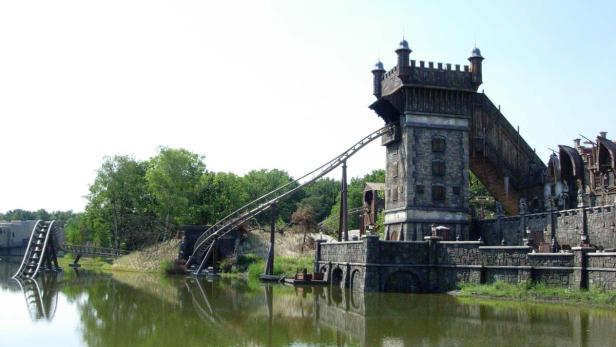 Eine Achterbahn schlängelt sich um einen Turm und über einen See.