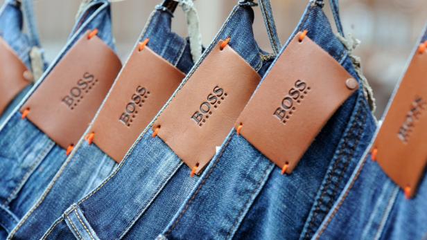 Mehrere Jeanshosen der Marke Boss hängen an einer Kleiderstange.