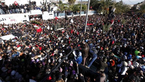 Mourners carry the coffin of slain opposition leader Chokri Belaid during his funeral procession towards the nearby cemetery of El-Jellaz, where he is to be buried, in the Jebel Jelloud district of Tunis February 8, 2013. Tens of thousands of mourners chanted anti-Islamist slogans on Friday at the Tunis funeral of secular opposition leader Belaid, whose assassination has plunged Tunisia deeper into political crisis. REUTERS/Anis Mili (TUNISIA - Tags: CIVIL UNREST POLITICS CRIME LAW OBITUARY)