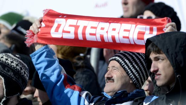 Ein Mann hält einen roten Schal mit der Aufschrift „Österreich“ in die Höhe.