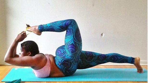 Eine Frau macht Yoga mit einem Gurt auf einer blauen Matte.