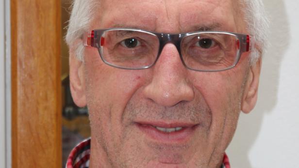 Porträt eines älteren Mannes mit Brille und kariertem Hemd.