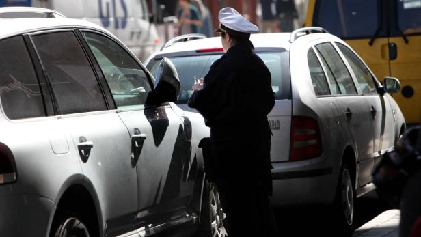 Eine Polizistin schreibt einen Strafzettel für ein parkendes Auto.