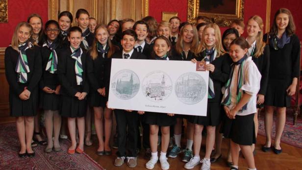 Eine Gruppe von Schülern hält eine Tafel mit Abbildungen von 10-Euro-Münzen „Wien“.