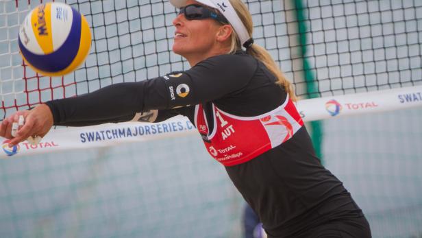 Eine Beachvolleyballspielerin schlägt den Ball über das Netz.