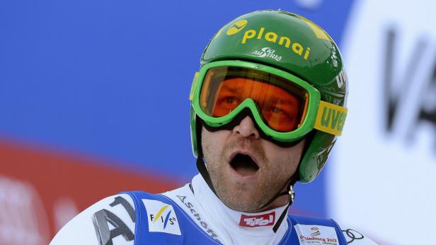 Ein Skirennläufer mit grünem Helm und Skibrille blickt überrascht.