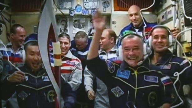 Eine Gruppe Astronauten lächelt und winkt in der Raumstation Mir.