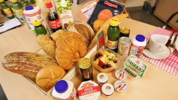 Ein Tisch mit Brot, Gebäck, Getränken, Obstsalat und verschiedenen Aufstrichen und Milchprodukten.