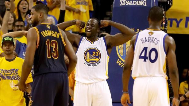 Draymond Green jubelt zwischen Tristan Thompson und Harrison Barnes auf dem Basketballfeld.