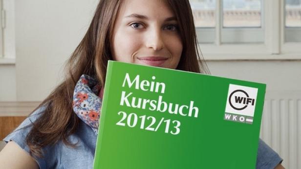 Eine junge Frau hält ein grünes Kursbuch des WIFI aus dem Jahr 2012/13 in die Kamera.