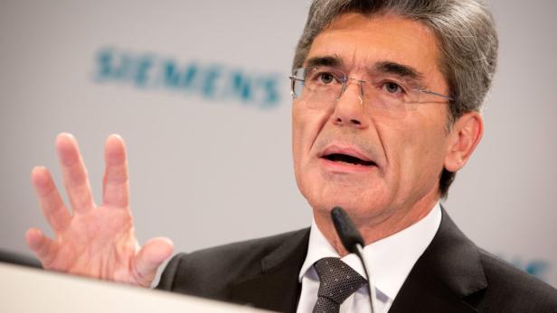 Ein Mann mit Brille gestikuliert vor einem Siemens-Logo.
