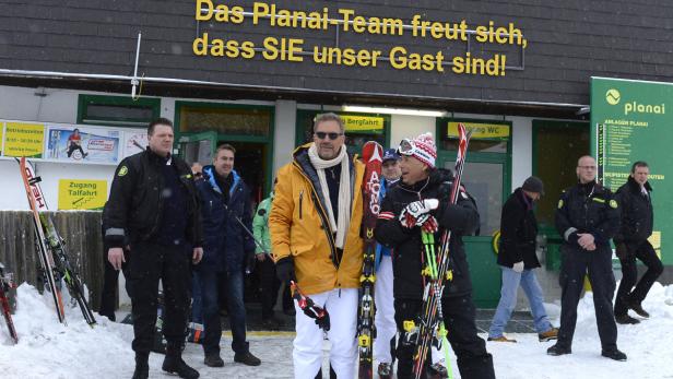 Eine Gruppe von Menschen steht vor dem Gebäude der Planai Bergbahn mit Skiern.