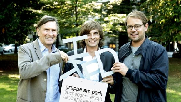 Drei Männer halten den Schriftzug „Gruppe am Park“ in einem Park.