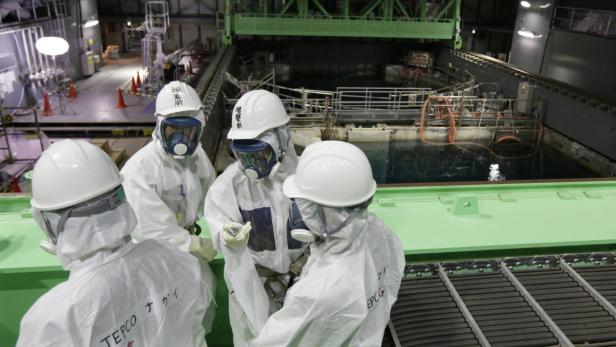 Arbeiter in Schutzanzügen inspizieren ein Becken im Kernkraftwerk Fukushima.