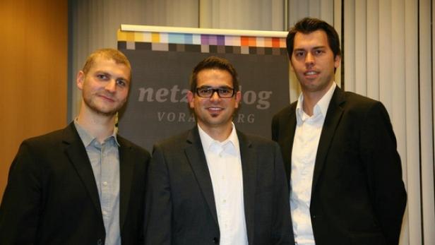 Drei Männer posieren vor einem „netzlog Vorarlberg“-Banner.