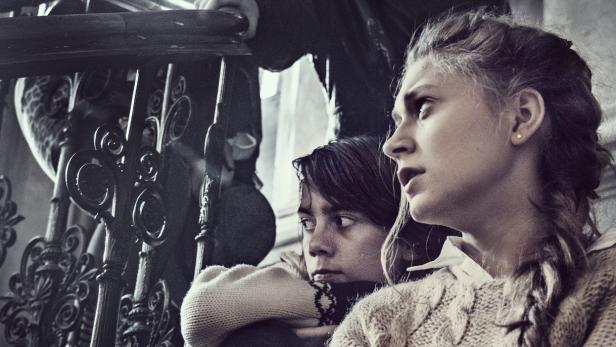 Zwei junge Frauen sitzen an einem Treppengeländer und schauen nachdenklich in die Ferne.