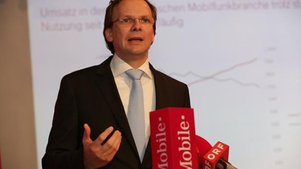Ein Mann in Anzug und Krawatte spricht vor Mikrofonen von T-Mobile und ORF.