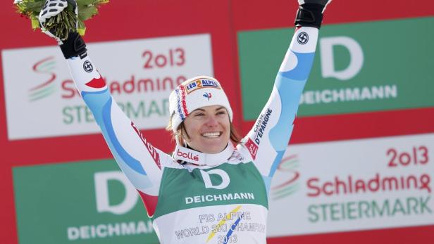 Eine strahlende Skirennläuferin feiert ihren Sieg mit erhobenen Armen.