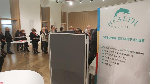 Besucher informieren sich auf einer Gesundheitsstraße über verschiedene Gesundheitstests.