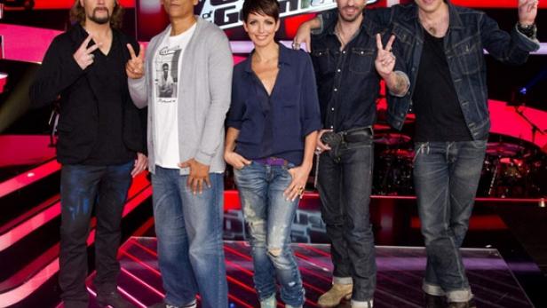 Die Jury von „The Voice of Germany“ posiert vor rotem Hintergrund und zeigt Victory-Zeichen.