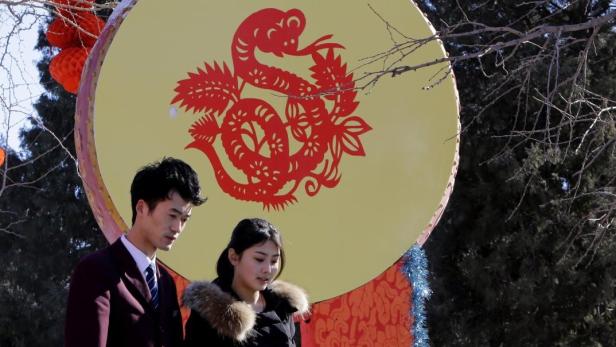 People walk past a Chinese decorative drum with a paper-cutting of a snake ahead of the Chinese Lunar New Year celebrations at Ditan Park (the Temple of Earth) in Beijing February 4, 2013. The Lunar New Year, or Spring Festival, begins on February 10 and marks the start of the Year of the Snake, according to the Chinese zodiac. REUTERS/Jason Lee (CHINA - Tags: SOCIETY)