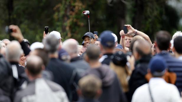 Tiger Woods inmitten einer Menschenmenge mit einem Golfschläger in der Hand.