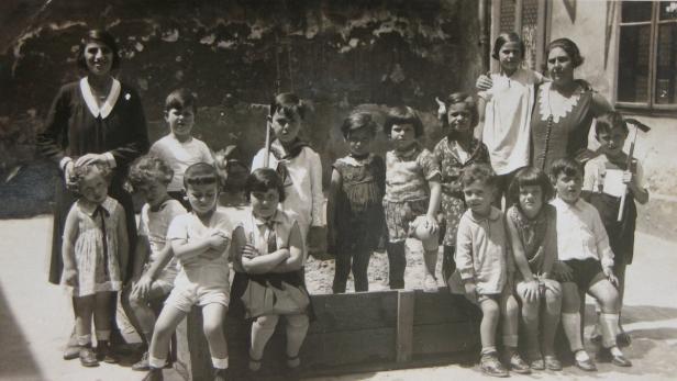 Eine Gruppe von Kindern und zwei Frauen posieren für ein Schwarzweißfoto.