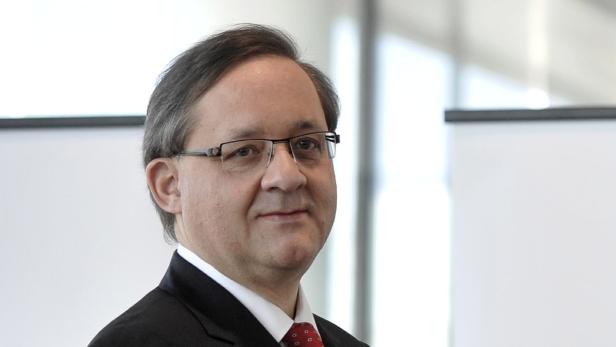 Ein Mann mit Brille und dunklem Anzug blickt in die Kamera.