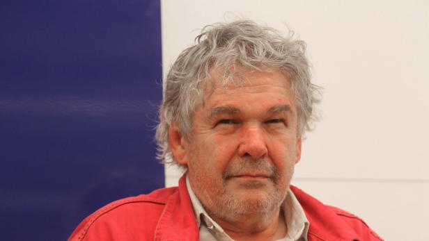 Porträt eines Mannes mit grauem Haar und roter Jacke.