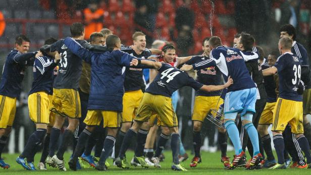Fußballspieler von Red Bull umarmen sich im Regen.