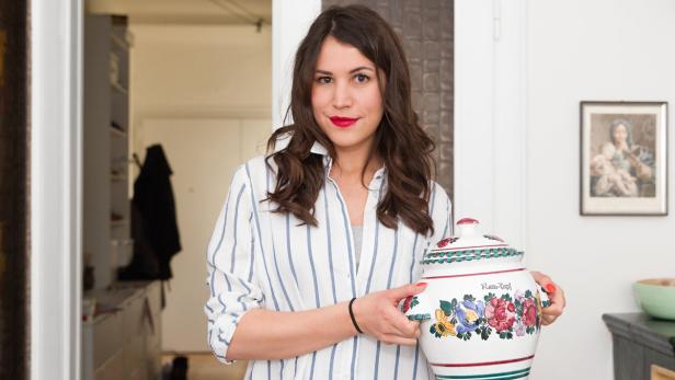 Eine Frau hält einen großen, bemalten Rumtopf in ihren Händen.