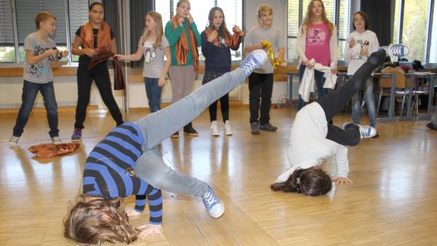 Zwei Mädchen machen Kopfstand vor einer Gruppe von Zuschauern.