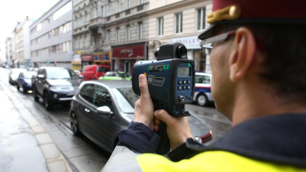 Ein Polizist misst mit einem Lasergerät die Geschwindigkeit von Autos in der Stadt.