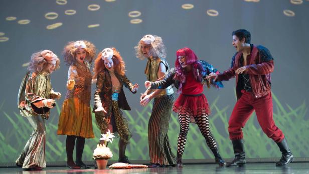 Eine Gruppe von Schauspielern in Kostümen und Masken steht auf einer Bühne.