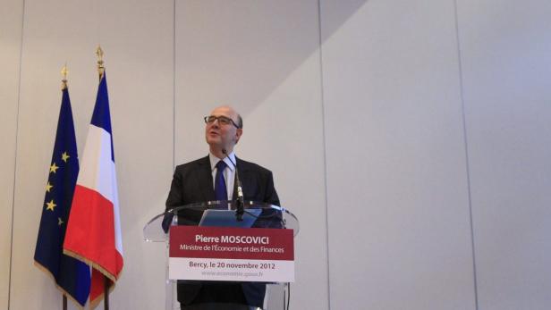 Pierre Moscovici, französischer Minister, hält eine Rede vor Flaggen der EU und Frankreichs.