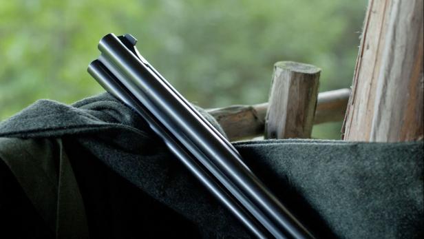 Ein Gewehr liegt auf einem grünen Stoff in einem hölzernen Unterstand.