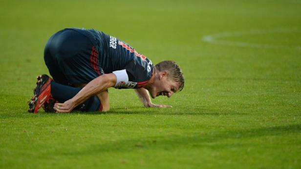 Ein Fußballspieler kniet auf dem Rasen und scheint Schmerzen zu haben.
