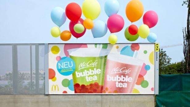 Eine McDonald's-Werbetafel für McCafé Bubble Tea mit bunten Luftballons darüber.