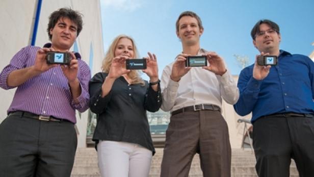 Vier Personen präsentieren Smartphones mit der Bounce-App vor einem Gebäude.