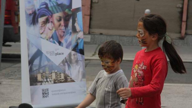 Zwei Kinder mit Tigermasken stehen vor einem Werbebanner.