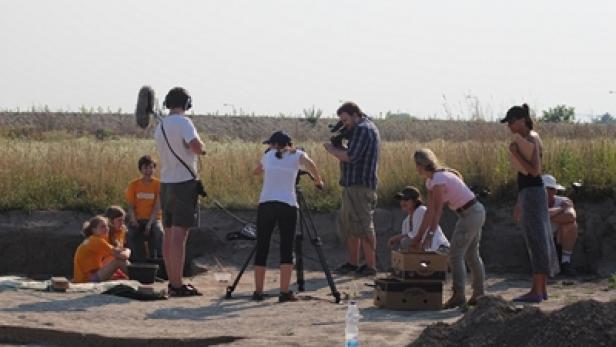 Ein Filmteam dreht eine Szene mit Kindern an einem sonnigen Drehort im Freien.