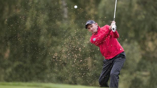 Ein Golfspieler schlägt einen Ball vom Rasen.