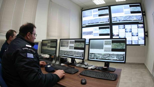 Zwei griechische Polizisten überwachen Überwachungskameras in einem Kontrollraum.