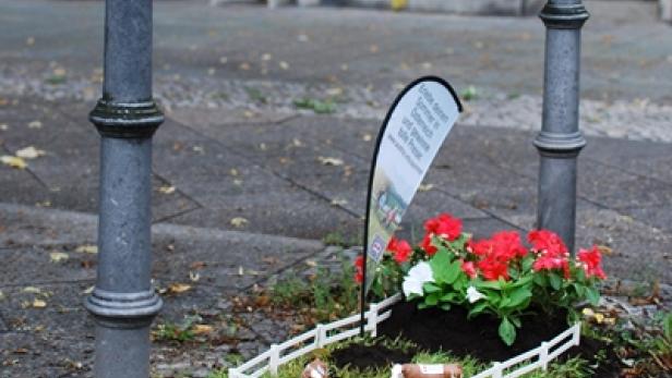 Eine Miniatur-Kuhweide mit Blumen und einem Werbebanner zwischen zwei Pfosten.