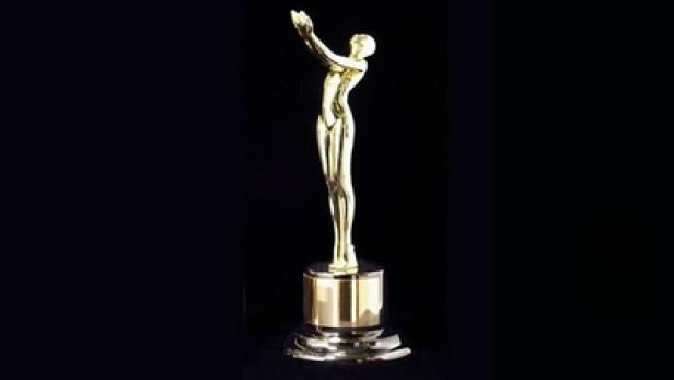 Eine goldene Statue einer Frau auf einem Sockel vor schwarzem Hintergrund.