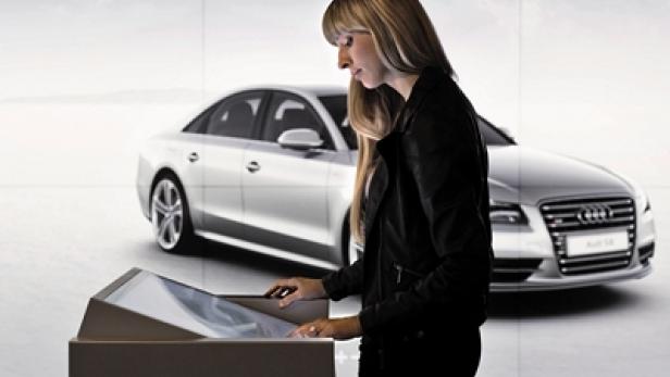 Eine Frau bedient ein interaktives Display vor einem Audi A8.