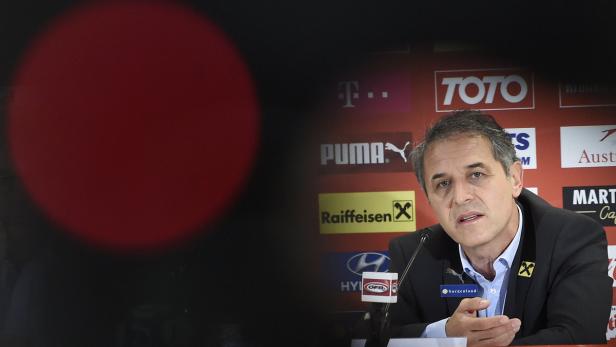 Ein Mann spricht vor einer Wand mit Sponsorenlogos.